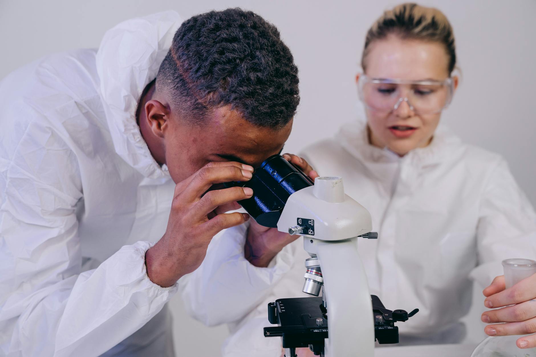 Dwóch naukowców w laboratorium ogląda próbki pod mikroskopem