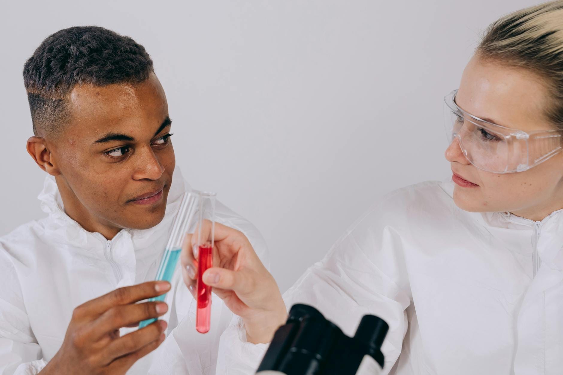 Dwóch naukowców w laboratoryjnych fartuchach analizuje probówki