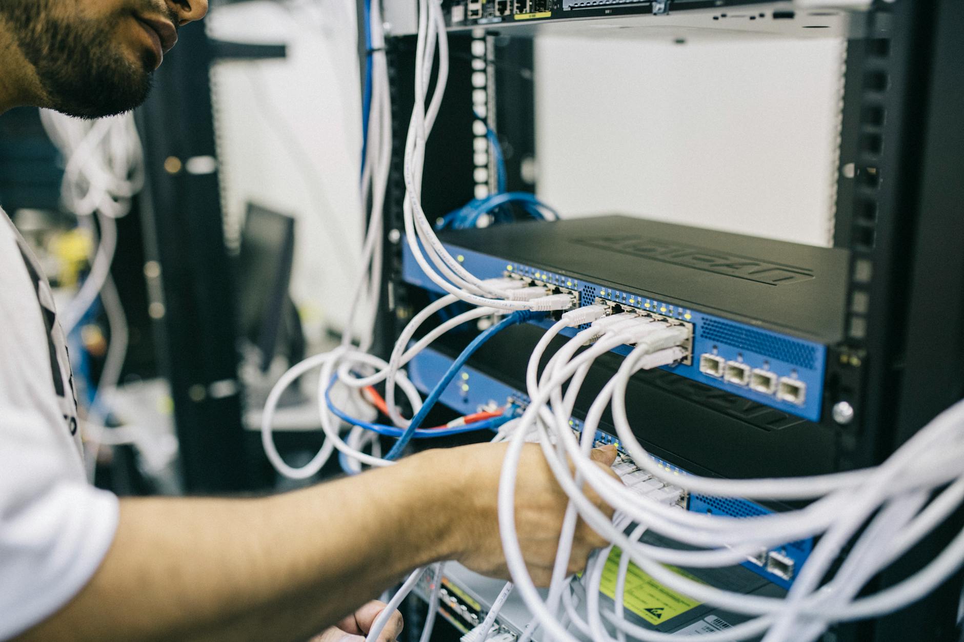 Informatyk podłącza kable Ethernet w szafie serwerowej