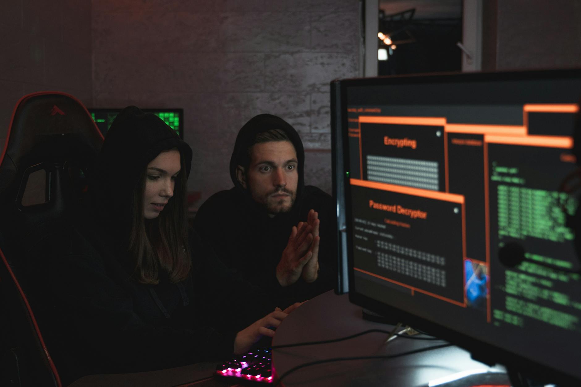 Specjaliści ds. cyberbezpieczeństwa w kapturach analizują dane na monitorach