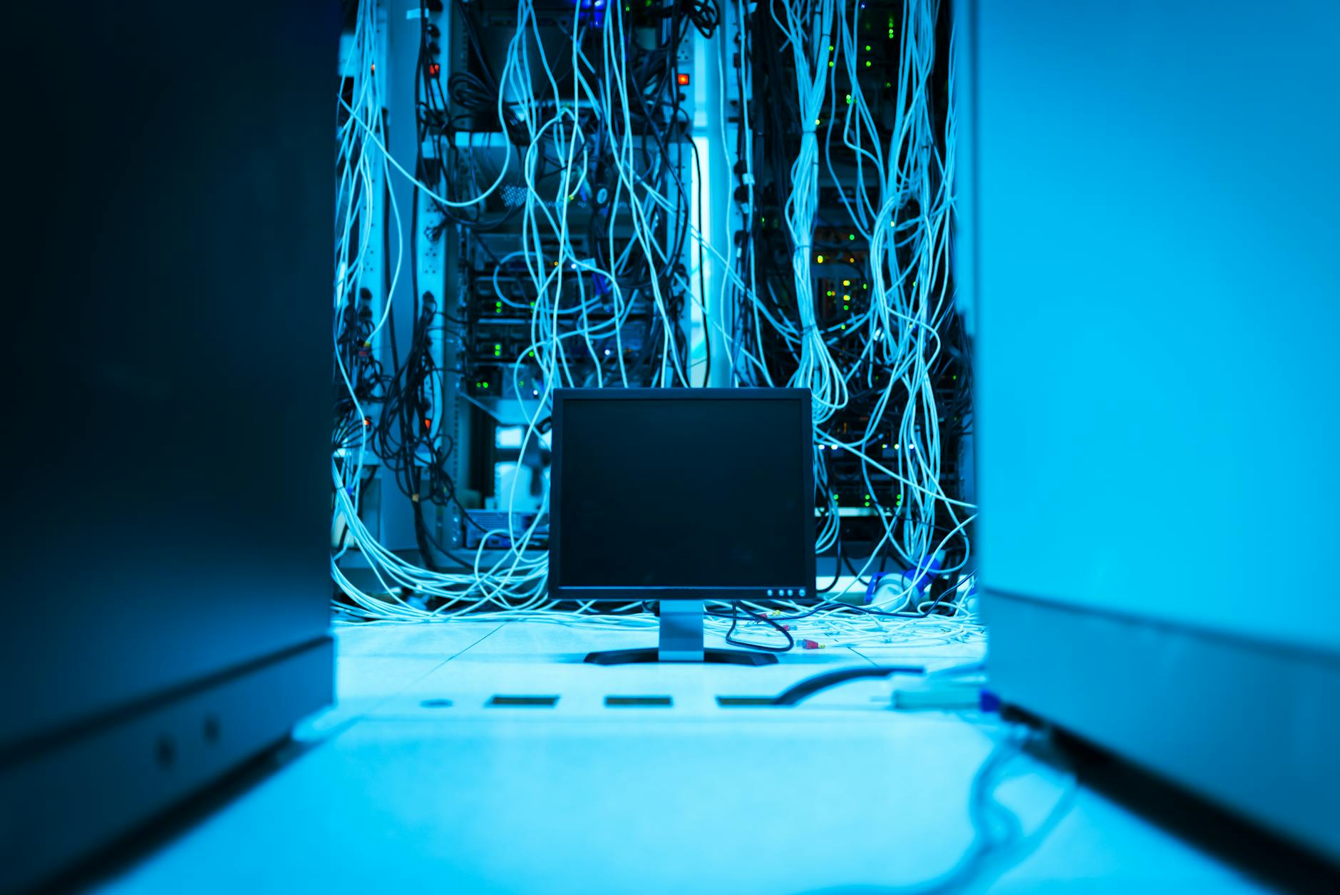 Monitor i plątanina kabli w centrum danych na tle serwerów