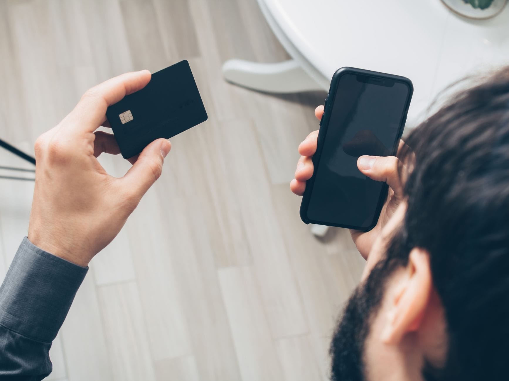Mężczyzna trzyma smartfon i kartę, wykonuje płatność online